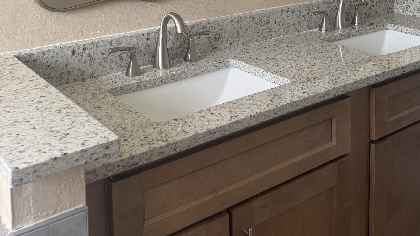 Bathroom vanity with granite countertop and undermount sinks after remodeling