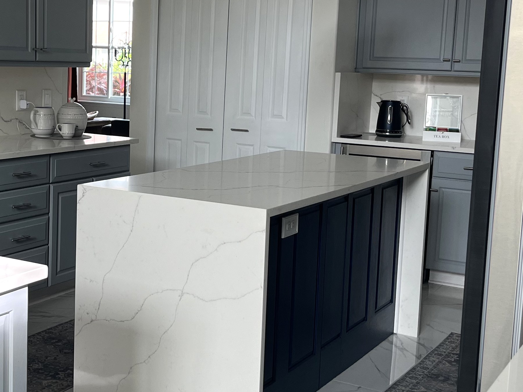 Navy kitchen island with a waterfall quartzite countertop