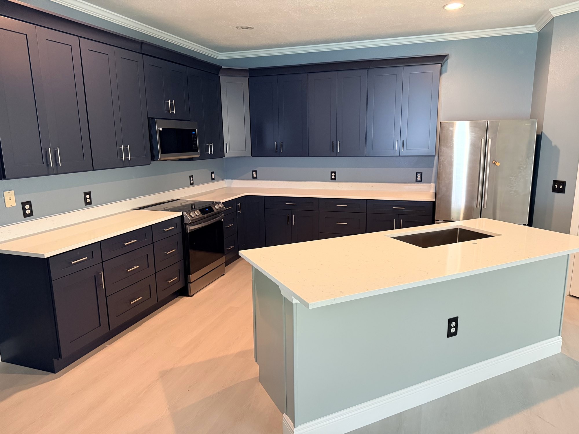 Navy shaker kitchen with white quartz counters and a pale blue island