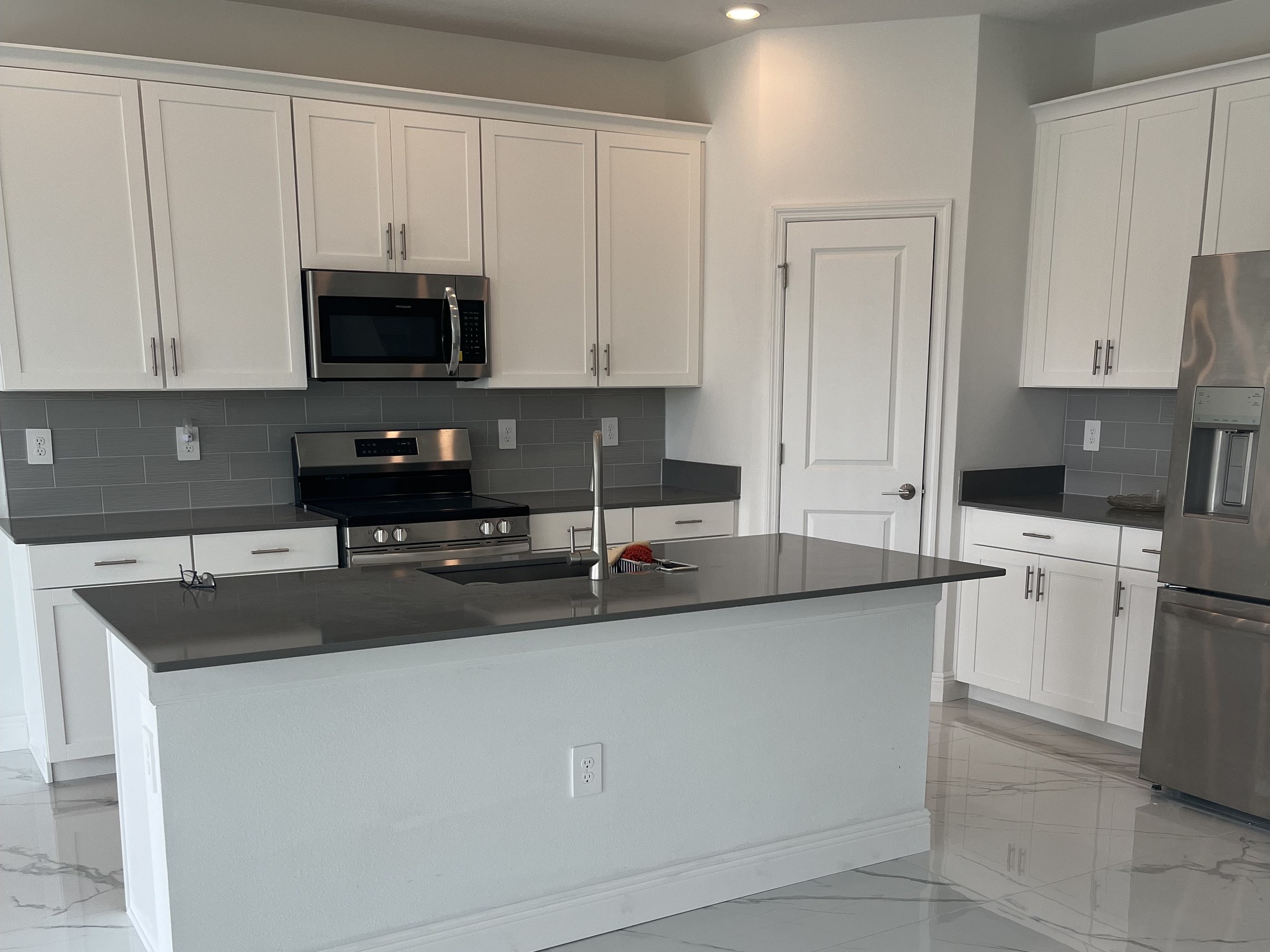 Glossy marble-look porcelain tile floor in a white kitchen