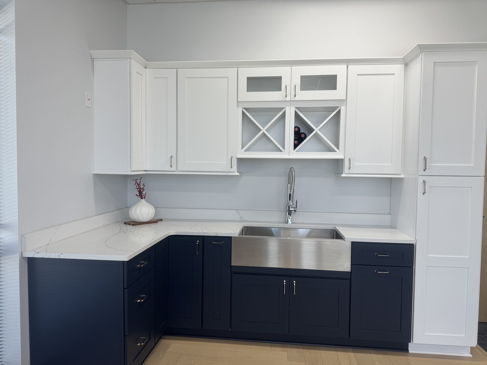 Showroom display with white upper cabinets, navy base cabinets, quartz counter and a stainless farmhouse sink